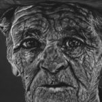 A hand drawn black and white charcoal pencil drawing of an old cowboy man